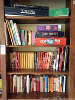 Bookshelves filled with assorted books and board games including Pictionary, Outburst!, Channel Surfing, Cranium, and others, as well as a globe.