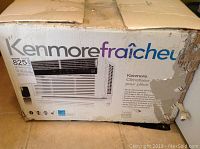 Damaged cardboard box showing Kenmore model 825 single room air conditioner packaging with product image and branding.