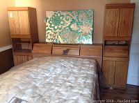 Full view of queen bed with wood headboard and two tall night stands on either side. Mosaic artwork above bed not included.