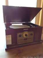 Top view of the Sylvania record player with lid open showing the turntable inside and front panel with control knobs and tuning dial.