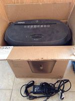 Paper shredder unit in open box showing control knob and power cord beside it.