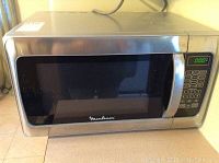 Front view of the Moulinex microwave oven showing stainless steel body and large glass window with the Moulinex logo