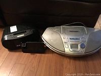 Sony Mega Bass CD player CFD-S50, Panasonic RX-ES25 cassette player radio, and large silver projector clock radio shown on wooden floor.