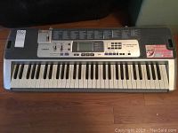 Full view of Casio LK100 keyboard showing 61 keys and control panel with buttons and sliders.