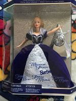 Full view of Barbie doll in box wearing dark purple velvet gown with silver embroidery and clear shawl, holding silver purse accessory.
