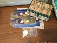 Photo showing vintage woven basket with stamp and coin collection, plastic sleeves with coins including large silver coin in ziplock bag.