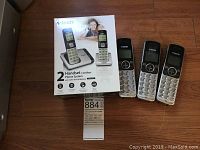 Photo of the VTech phone system box and three cordless handsets on wooden floor.