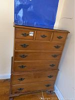 Photo showing the front of the wooden dresser with visible metal handles and three small drawers on top and five large drawers below. Shows wear and marks on wood.