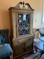 Full front view of the wooden china cabinet showing the glass door with wooden lattice, and lower storage section.