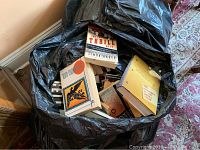 Photo of a large black bag filled with various books showing titles such as 'Thrill Me' and 'Song of Solomon.'