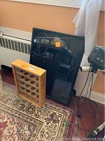 Photo showing two display cases placed on the floor against the wall, one wooden case with keys and a large black shadow box case.