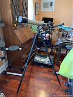 Full view of Omega refractor telescope on adjustable tripod stand set indoors.