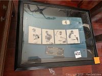 Framed display case showing the seatback, four player photos, and plaque inside.
