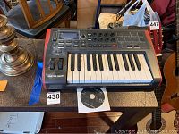 Front view of Novation Impulse 25 MIDI keyboard on table with DVD underneath.