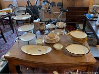 Photo showing Lenox serving bowl, Limoges bowls with some chips, Rosenthal condiment dishes, three-tier serving server with decorative plates, and other dishes arranged on a wooden table.