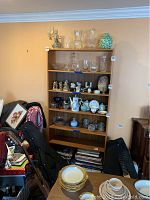 Front view of tall wooden bookcase with glassware and knickknacks on shelves, items not included in sale.