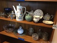 Shelf display of assorted porcelain and crystal items, including coffee pot, teapots, crystal bowls, pewter bowl