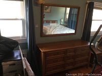 Wide view of the dresser with mirror hung above it, showing the furniture arrangement, lighting and some room reflection