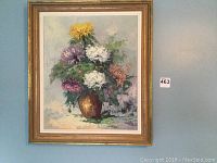 Full view of the framed painting depicting flowers in a vase hung on a wall.