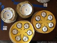 Porcelain tea cups and berry bowls housed in yellow fitted cases, displaying the bottoms of each cup marked with Furstenberg Lottine.