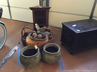 Overview of several baskets, metal urns, and wood tray arranged in front of the wood corner shelf