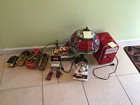 Photo showing entire lot on tile floor including Tiffany style lamp, cooler, snow globe, trucks, and napkin holder.