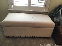 Front view of linen upholstered chest bench showing rectangular shape and beige fabric.