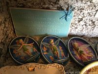 Four limited edition Tinkerbell plates with 3D wings displayed together, blue backgrounds with whimsical designs and Certificates of Authenticity on the back