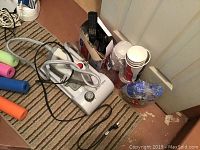 Photo showing EuroPro clothing steamer, iron with cords and various party supplies including plastic cups and cutlery.
