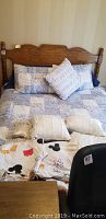 Full view of queen bed setup showing the bed made with patchwork and striped comforters, multiple pillows, and partially visible bed frame and headboard.
