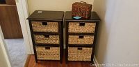 Front view of two dark wood drawer units, each with three wicker basket drawers, placed side by side on hardwood and carpet flooring.
