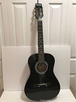 Full front view of the black Nova acoustic guitar showing the body and neck against a white background.