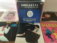 Five LP vinyl records laid out on a flat surface showing album covers for Chris G.O.T.T.I., Elvis Presley, John Stewart, Hit Parade compilation and another album.