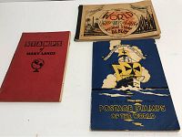 Three vintage stamp albums arranged flat on a table showing front covers including The World United States & Foreign Postage Stamp Album, the Red Rose Postage Stamps of the World album, and a red Stamps of Many Lands album.