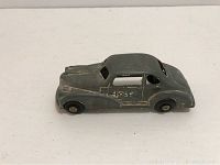 Side view of the vintage gray wind-up metal police car showing chipped paint and the word POLICE on the door.