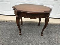 Front angled view showing scalloped edges of the top, ornate apron carvings, and curved legs.