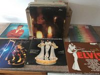 Photo showing a selection of used LP records with covers including Tony Orlando & Dawn Greatest Hits, Tribute to Elvis, and others arranged standing up on a table.