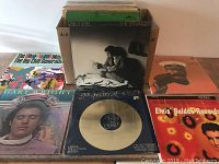Photo showing a selection of vinyl LP records in a box and displayed in front, featuring 'The Stranger' by Billy Joel and 'Elvis Golden Records'.