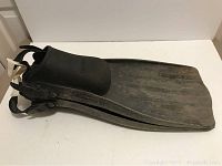 Side view of the pair of black scuba diving fins with closed heel straps and adjustable buckles stacked on top of each other.