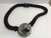 Full view of the regulator with the hose forming a loop showing metal body and hose attachment points.