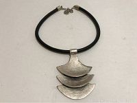 Front view of the necklace showing the black leather rope and pendant with hammered silver-tone finish.