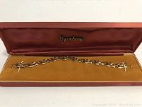 Full view of bracelet laid in open red Symphony box with golden velvet interior.