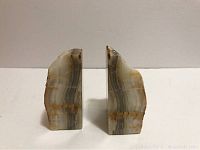 Pair of natural stone bookends viewed front facing, showing smooth stratified stone with grey, white, and brown layers