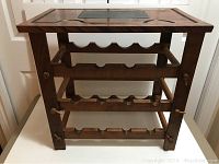Front view of wooden wine stand showing removable tray top and three shelves with scalloped rails for bottles.