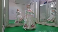 Front full view of the Royal Doulton figurine June showing its dress and face details with reflections in mirrors behind.