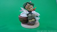 Front view of Hummel Barnyard Hero figurine showing the child with rabbits in the basket sitting on a round base.