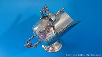 Silver plated sugar container shaped like antique coal scuttle with detailed handle and floral engravings