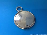 Front view of round silver hand mirror with monogram and handle on blue background