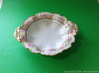 Full view of the Limoges serving plate showing pink rose motifs and gold gilt accents on the scalloped edges and handles.
