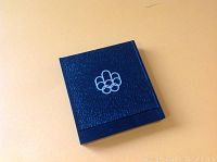 Blue textured presentation case with silver Olympic rings logo on cover.